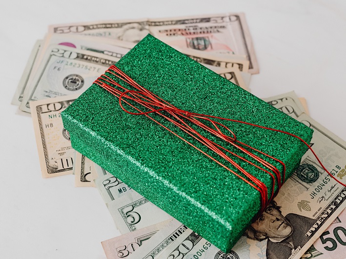 Zielone pudełko z czerwonym sznurkiem i dolary 