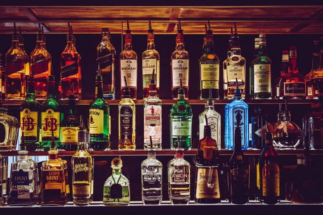 Półki, na których w równych rzędach stoi alkohol w butelkach.