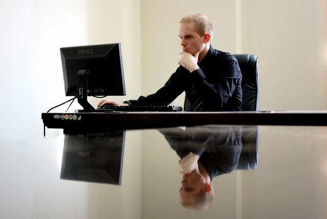 Mężczyzna siedzący w pustym biurze przed laptopem.