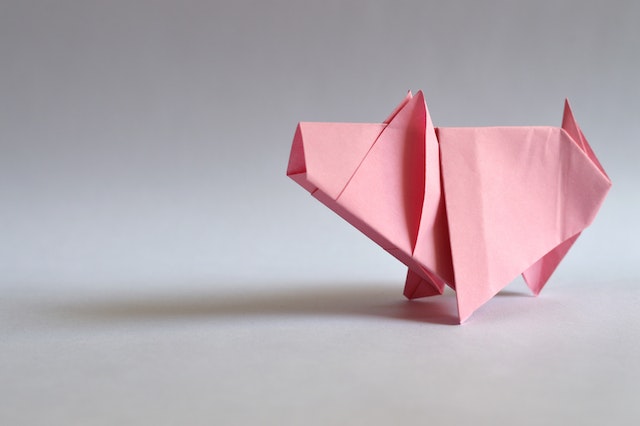 Różowa świnka origami na szarym tle.